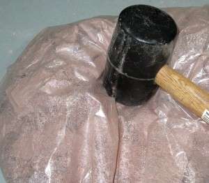 breaking dry clay with a mallet